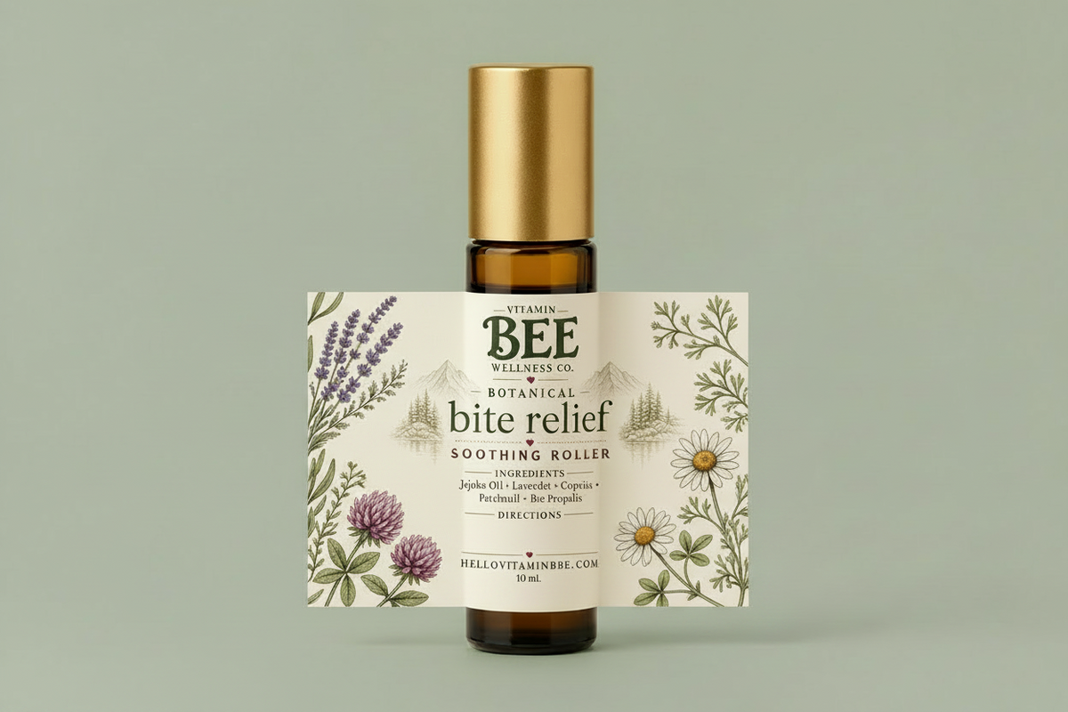 An amber glass bottle with a metallic gold cap and a detailed botanical label for 'Vitamin Bee Wellness Co. Botanical Bite Relief Soothing Roller', set against a solid sage green background.